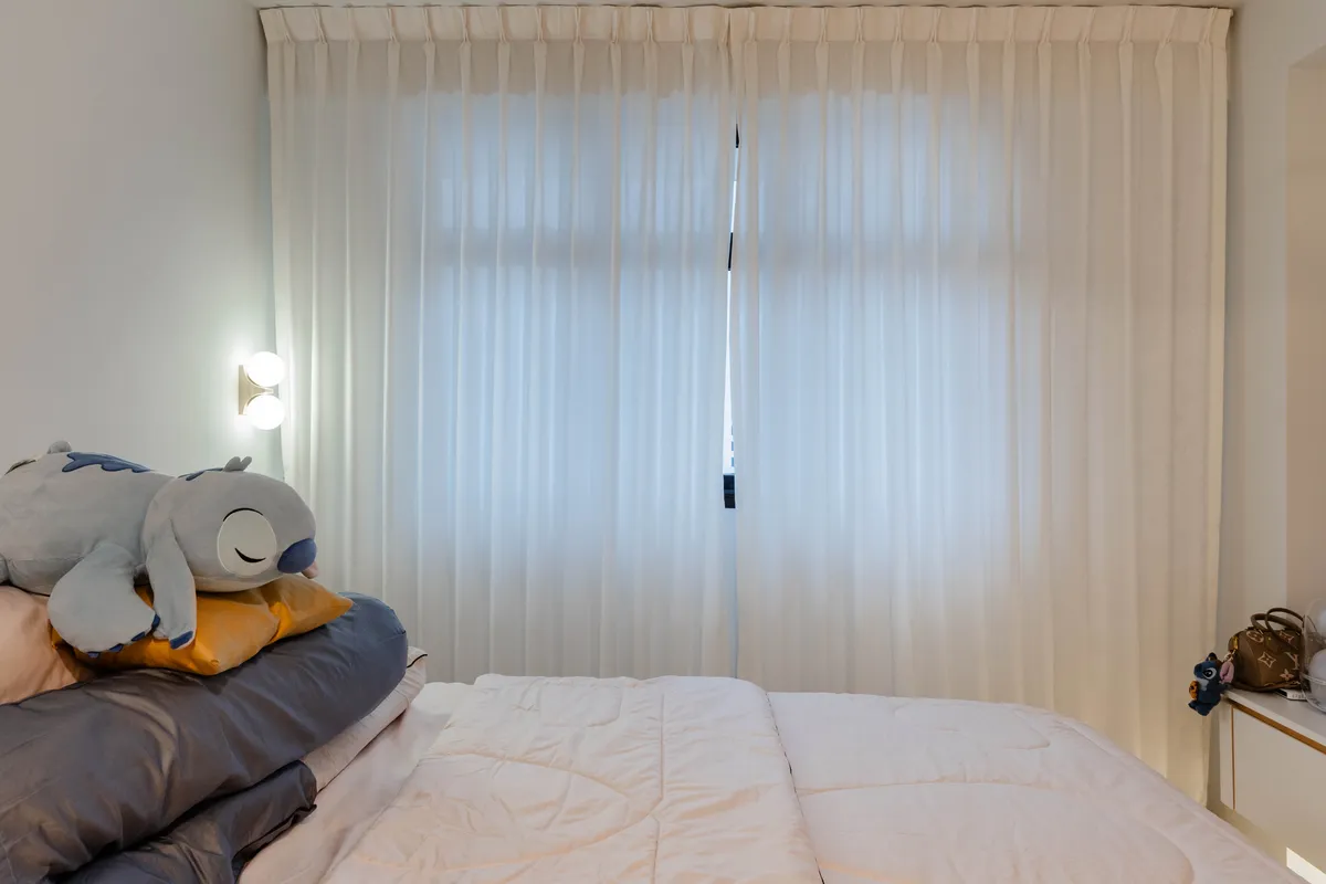 Bed dressed beside full height curtains at Fernvale St